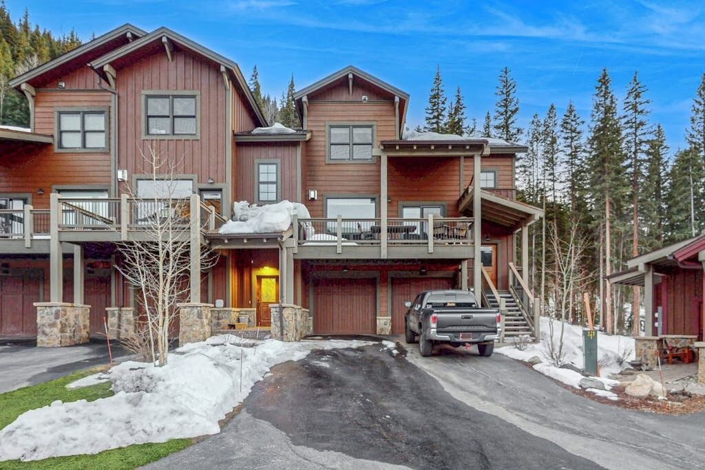 A multi-story wooden house with a garage, a covered porch, and a staircase leading to the upper level.