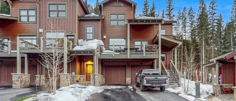 A multi-story wooden house with a garage, a covered porch, and a staircase leading to the upper level.