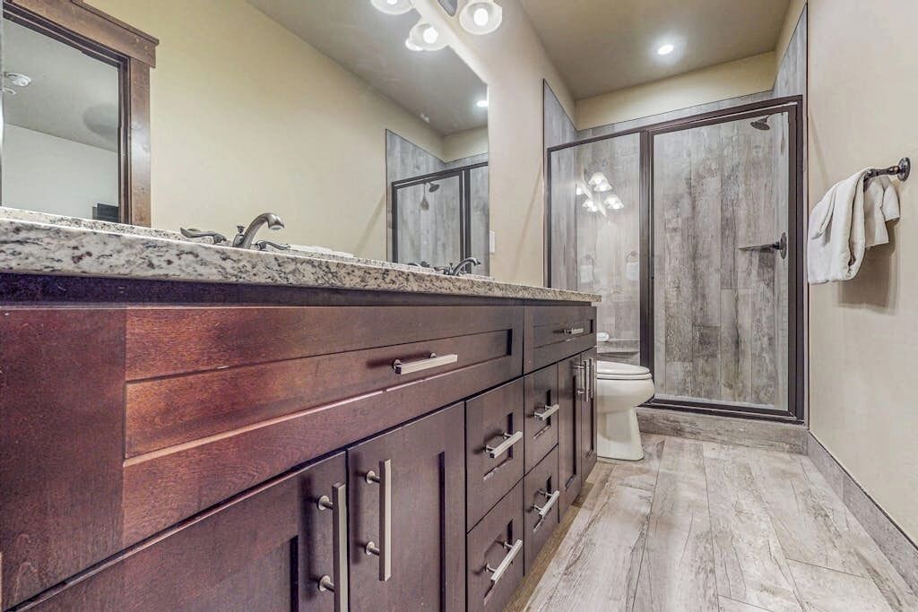 A bathroom with a large vanity, a shower, and a toilet.