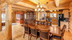 L’intérieur d’une cabane en rondins comprend un coin repas, une cuisine et une grande table à manger en bois, ainsi que des chaises.
