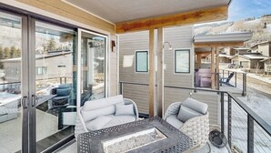A balcony with a glass door, wicker furniture, and a fire pit. - Modern mountain home with W/D, hot tub, full kitchen & near ski resort (Durango)