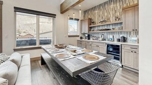 A modern kitchen with a large island, wooden beams, and a view of the mountains. - Modern mountain home with W/D, hot tub, full kitchen & near ski resort (Durango)