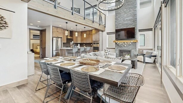 A spacious dining area with a high ceiling, modern kitchen, and a fireplace. - Modern mountain home with W/D, hot tub, full kitchen & near ski resort (Durango)