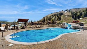 A swimming pool with lounge chairs, a covered seating area, and a ski lift in the background. - Modern mountain home with W/D, hot tub, full kitchen & near ski resort (Durango)