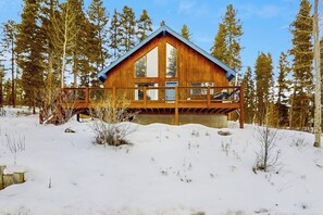 Eine Holzhütte mit einem Balkon, umgeben von Schnee und Bäumen.