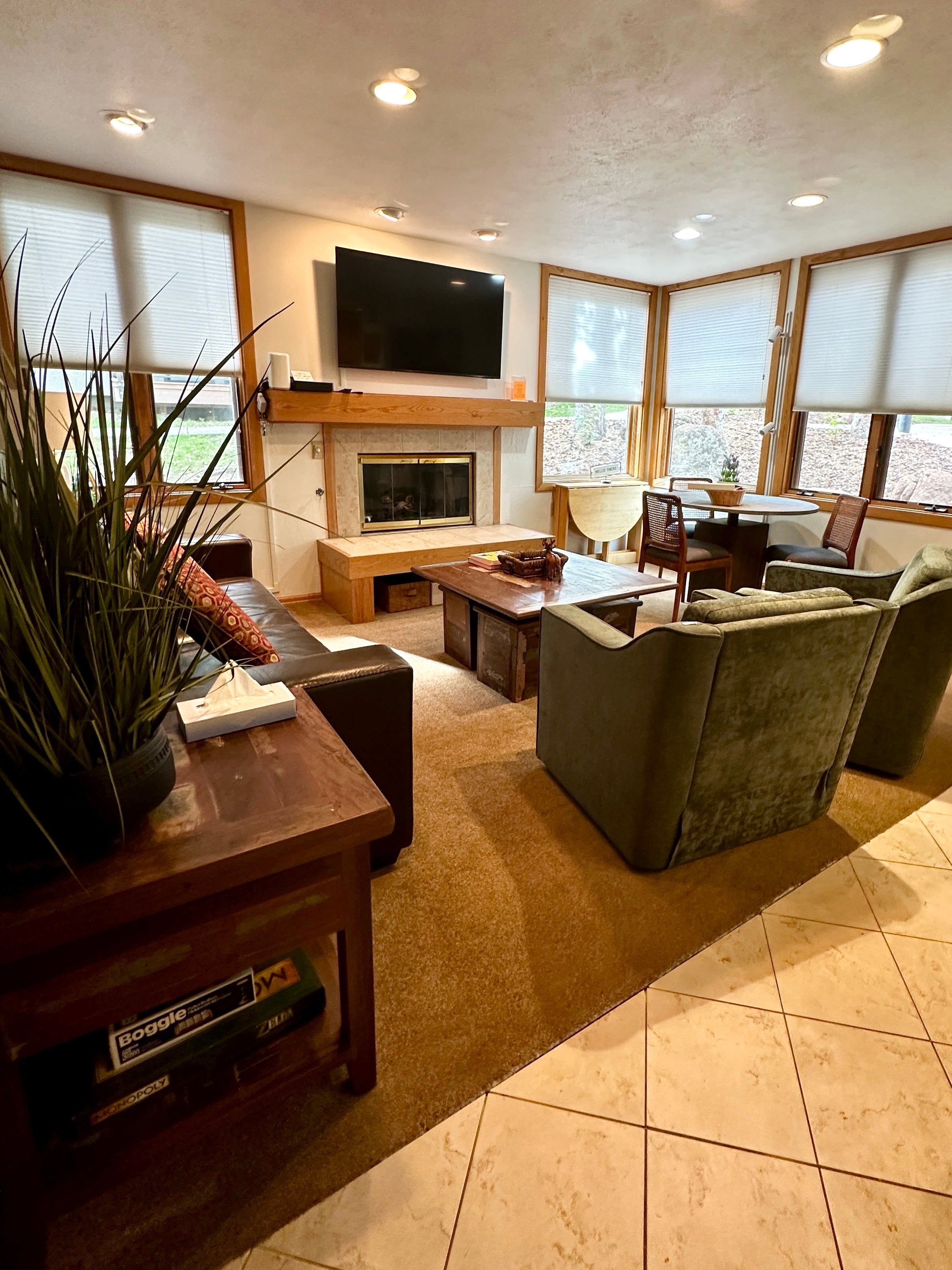 A modern living room with a fireplace, a flat-screen TV mounted above it, and a seating area with a sofa and chairs.