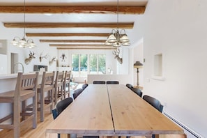 Ein Essbereich mit einem langen Holztisch, Stühlen und einer Kronleuchter.