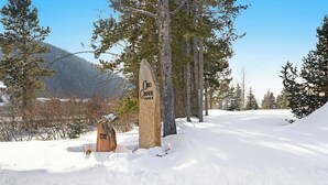 Eine verschneite Landschaft mit einem Holzschild für ORO Grande Lodge.