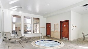 Ein Wellnessbereich mit Whirlpool, Liegestühlen und Blick durch große Fenster.