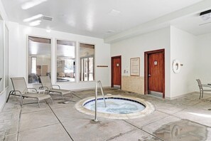 Ein Wellnessbereich mit Whirlpool, Liegestühlen und Blick durch große Fenster.