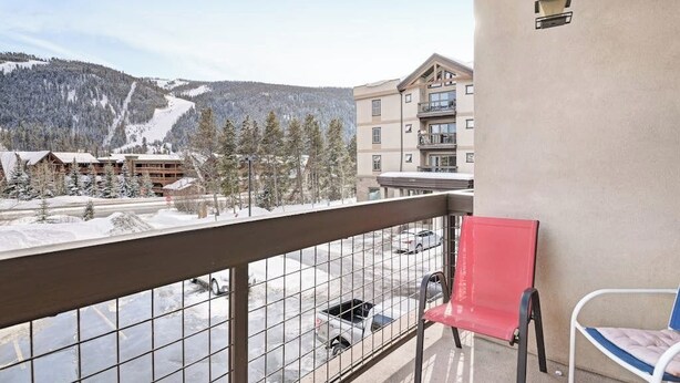Ein Balkon mit Blick auf einen Skigebiet, ein roter Sessellift und ein mehrstöckiges Gebäude.