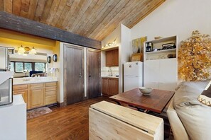 A modern kitchen with wooden cabinets, a dining table, and a sofa. - Studio condo w/ wifi, kitchenette, shared pool & hot tub - near golf & skiing (Durango)