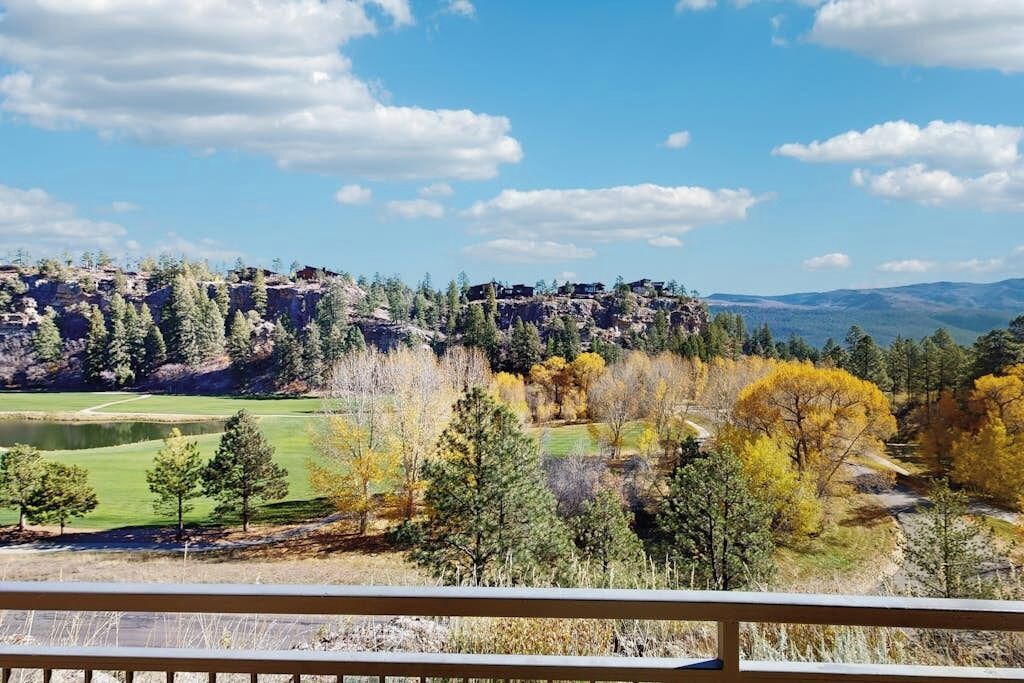 A scenic view of a mountainous landscape with a golf course and autumn foliage.