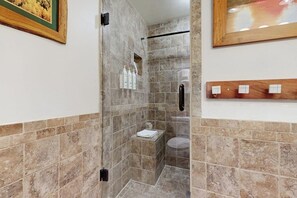 A bathroom with a shower, a toilet, and a sink. There are toiletries on the wall. - Spacious studio with lovely view and access to shared pool and hot tub (Durango)