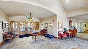 A spacious lobby with a high ceiling, a reception desk, a seating area with chairs, and a coffee table. - Cozy resort studio - Walk to lifts, shops, restaurants & entertainment (Keystone)