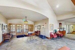 A spacious lobby with a high ceiling, a reception desk, a seating area with chairs, and a coffee table. - Cozy resort studio - Walk to lifts, shops, restaurants & entertainment (Keystone)