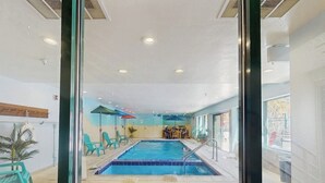 An indoor swimming pool with blue tiles, a diving board, and a seating area with chairs and umbrellas. - Cozy resort studio - Walk to lifts, shops, restaurants & entertainment (Keystone)