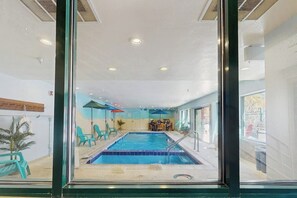 An indoor swimming pool with blue tiles, a diving board, and a seating area with chairs and umbrellas. - Cozy resort studio - Walk to lifts, shops, restaurants & entertainment (Keystone)