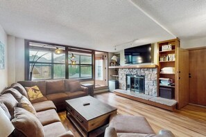 Ein Wohnzimmer mit Kamin aus Stein, einer Couch, einem Couchtisch und einem Bücherregal.