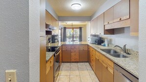 Une cuisine compacte avec des meubles en bois, un plan de travail en granit et un four encastré.