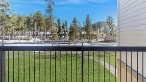 Un balcon donnant sur un espace verdoyant, des arbres et un bâtiment situé au loin.