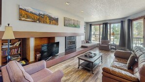 Un salon avec une cheminée, un téléviseur, un canapé et une bibliothèque.