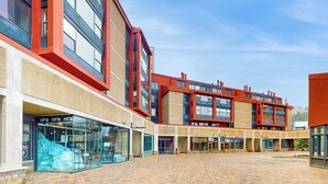 Um edifício moderno com fachada de tijolos, janelas amplas e um pátio.
