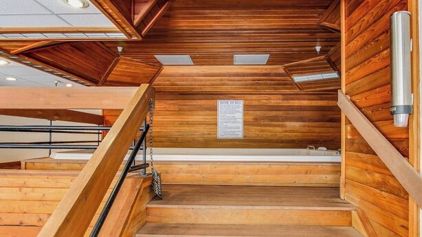 Interior em madeira com escada que leva a uma área com banheira de hidromassagem.