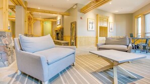 A room with a sofa, a table, and a stone wall. - Family-friendly mountain condo w/balcony, shared hot tub, & mountain views (Copper Mountain)