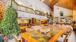 A spacious living area with a large wooden dining table, a Christmas tree, and a staircase leading to an upper level. - Ski-In/Ski-Out Studio with Gas Fireplace & Shared Pool, Hot Tub, Gym,  Game Room (Winter Park)