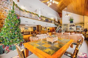 Ein großzügiger Wohnbereich mit einem großen Holztisch, einem Weihnachtsbaum und einer Treppe, die in eine obere Etage führt.