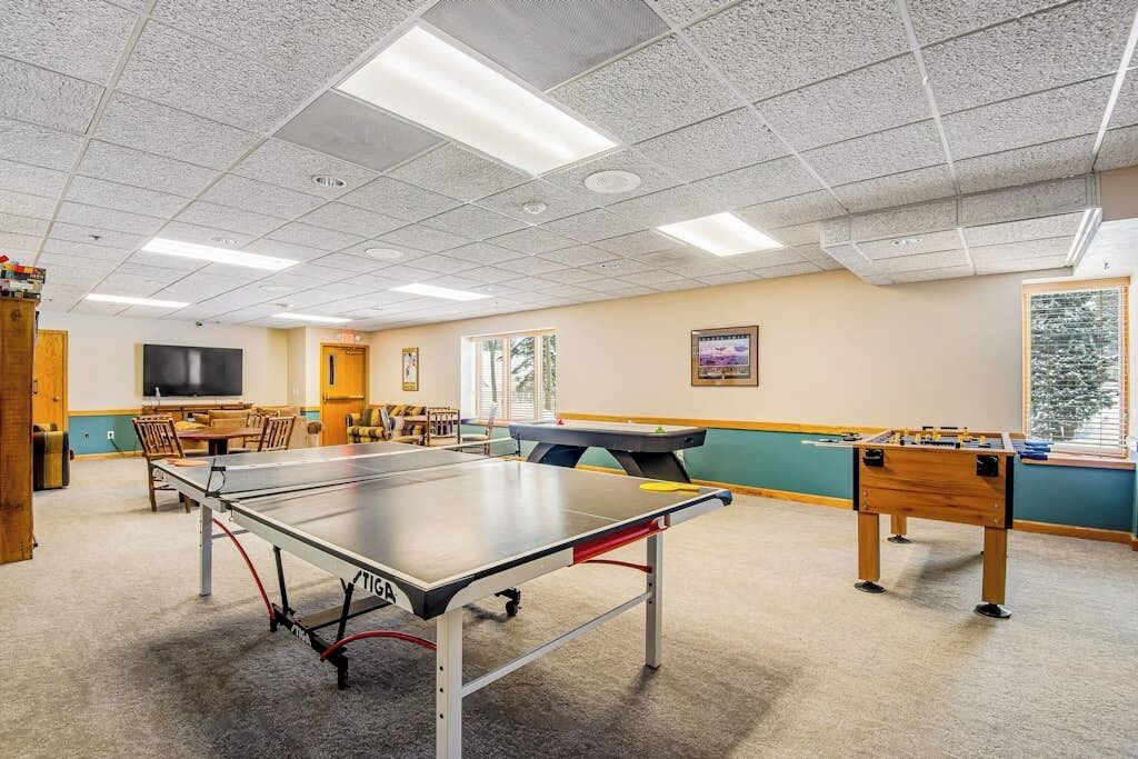 Una sala de recreación con mesa de ping pong, mesa de futbolín y mesa de billar.