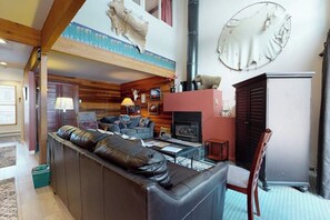 Ein Wohnzimmer mit Kamin, Ledersofa und einem aufgehängten Tierkopf.