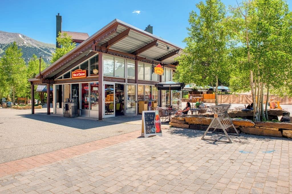 A restaurant with a sign reading 'Map of Cheese,' outdoor seating, and a mountain backdrop.