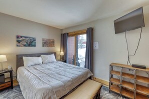 Ein Hotelzimmer mit Bett, Fernseher, Bildern an der Wand und einem Fenster mit Vorhängen.
