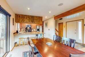 A dining area with a wooden table and chairs, a kitchen with wooden cabinets, and a sliding glass door.