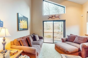 A living room with two sofas, a lamp, a framed picture, and a sliding glass door leading to an outdoor deck.