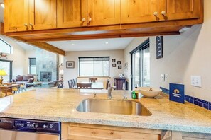 A kitchen with granite countertops, wooden cabinets, a stainless steel sink, and a dishwasher.