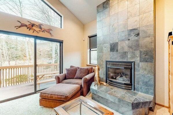 A living room with a stone fireplace, a brown leather sofa, and a glass coffee table.
