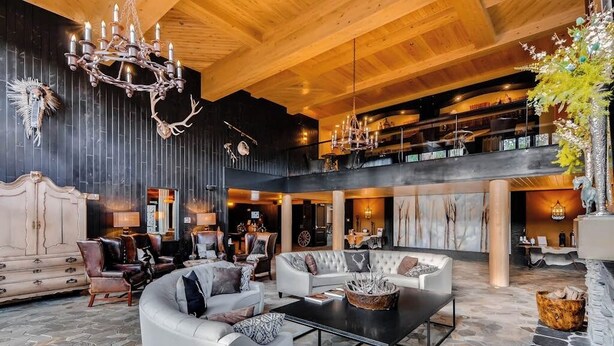 Un'ampia hall con soffitto alto, un sontuoso lampadario, divani in pelle e un pavimento in pietra.