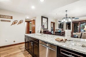 Eine moderne Küche mit Granit Arbeitsplatte, Edelstahlgeräten und Holzkorpusen.