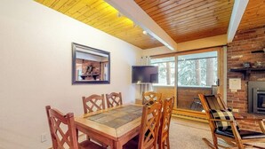 A dining area with a wooden table and chairs, a television, and a fireplace. - Cozy, comfortable condo with pool & hot tubs - walk to lifts & Main Street (Breckenridge)