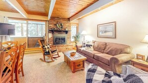 A cozy living room with a fireplace, wooden furniture, and a large window. - Cozy, comfortable condo with pool & hot tubs - walk to lifts & Main Street (Breckenridge)