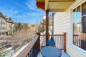 Ein Balkon mit Stuhl, Geländer und Blick auf benachbarte Gebäude.