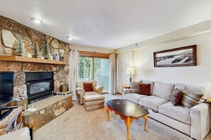 Ein Wohnzimmer mit Kamin, Sofa, Couchtisch und Fernseher.