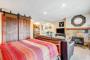 Une chambre à coucher avec un lit, une cheminée, une télévision et une porte coulissante de style grange.