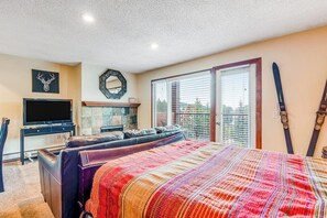 Een slaapkamer met een bed, een televisie, een open haard en een ski-rek.
