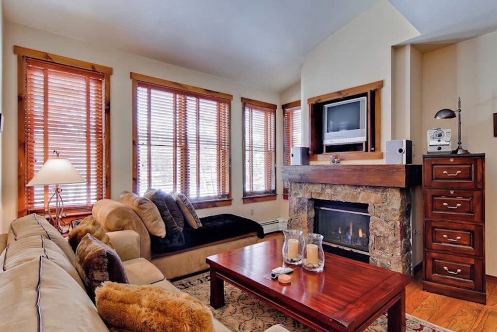 A living room with a fireplace, a sofa, a coffee table, and a television.