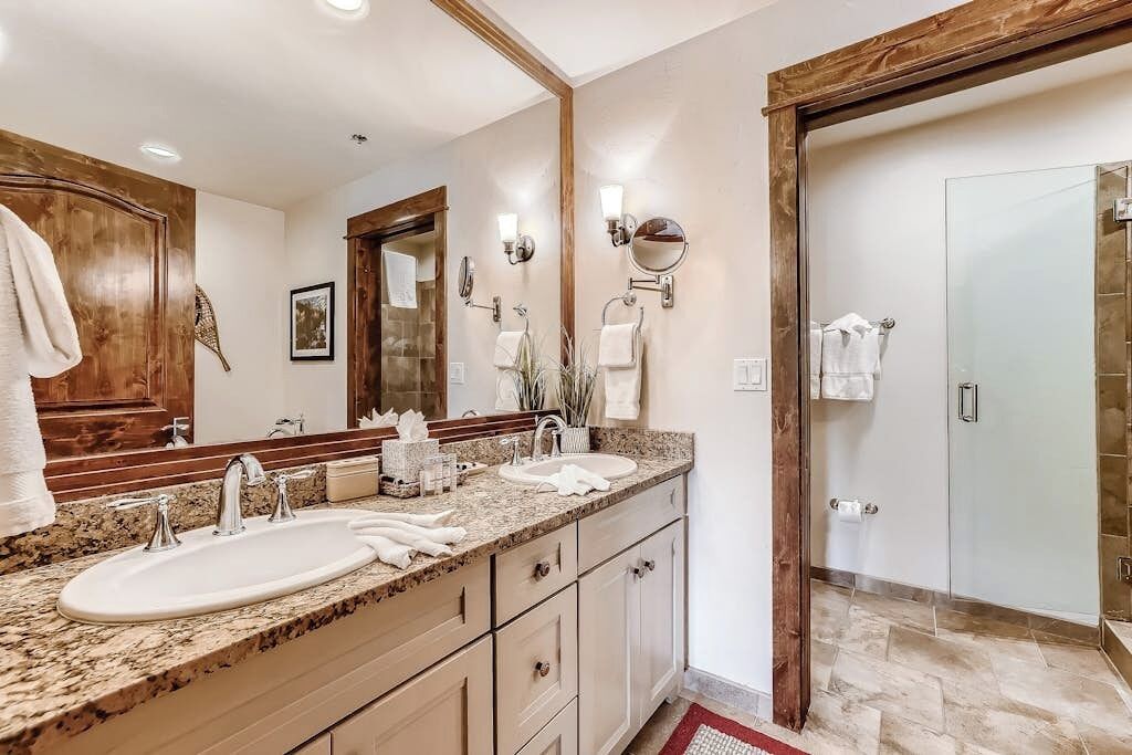 A bathroom with a double sink, a large mirror, and a shower area.