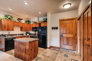 A kitchen with wooden cabinets, a black refrigerator, and a central island. - Downtown condo near QuickSilver Lift with river view, pool & hot tubs (Breckenridge)